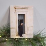 Carte postale représentant un homme âgé debout devant une porte ancienne en pierre claire à Martina Franca